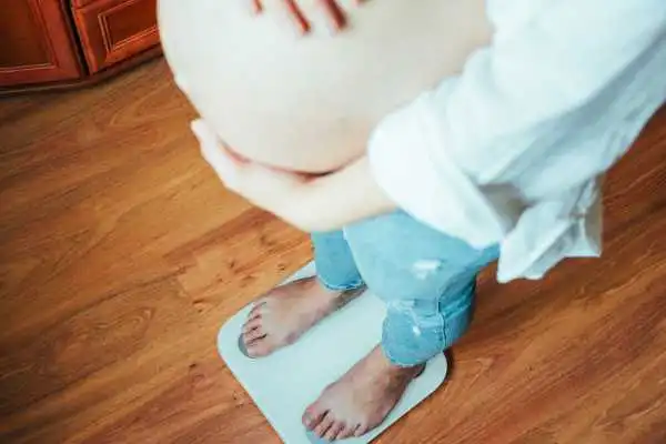 Image of woman weighing herself and experiencing weight gain through pregnancy Buckingham